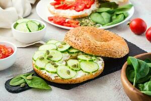 Delicious bagel stuffed with feta, cucumber and pumpkin seeds and spinach leaves on a slate board. Light Vitamin Healthy Snack. Close-up photo