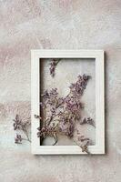 Dry purple flowers in a wooden frame on a textured background. Romantic greeting vintage card. Top and vertical view photo