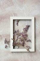 Dry purple flowers in a wooden frame on a textured background. Romantic greeting vintage card. Top and vertical view photo