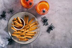 Halloween treat salty bread sticks with pumpkin seed nails with ketchup on a plate top view photo