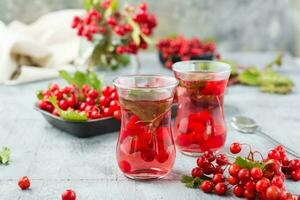 A decoction of ripe viburnum berries in transparent glasses on the table. Alternative medicine, vitamin nutrition and wellness photo