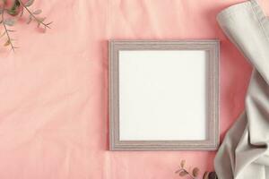 Mockup empty photo frame and branches on pink cotton fabric top view