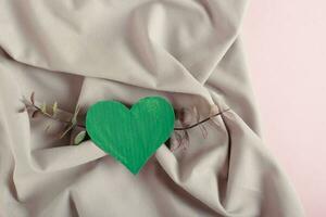 Green cardboard heart and eucalyptus branches on a background of green crumpled cotton fabric photo