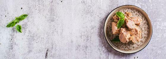 Canned tuna fish meat and basil on a plate on the table top view web banner photo