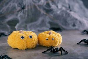 Halloween knitted pumpkins with eyes and spiders with cobwebs on a gray background photo