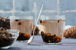 Decoction of pine nut shells in glasses, pine nuts and cones on the table. Alternative medicine. photo