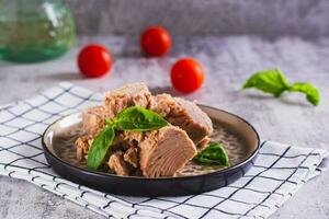 Pieces of canned tuna and basil leaves on a plate photo