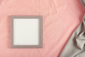 Blank photo frame template on pink cotton fabric top view
