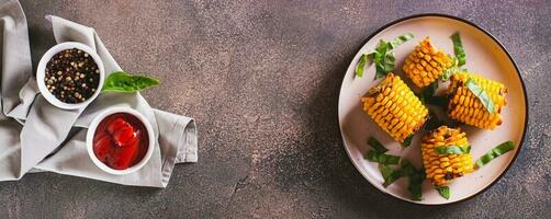 Grilled corn with spices, butter and garlic on a plate on the table top view web banner photo