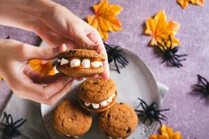 de cerca pan de jengibre galletas con malvavisco dientes en para niños manos para Víspera de Todos los Santos parte superior ver foto