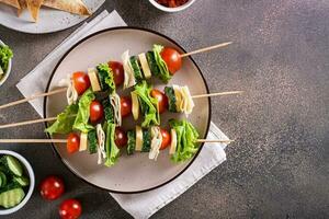 bocadillo en brochetas de Tomates, pepino, queso, Agave un pan y lechuga en un plato parte superior ver foto