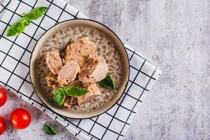 Pieces of canned tuna and basil leaves on a plate top view photo