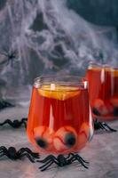 Non alcoholic red cocktail with eyeballs and orange in glasses on the table vertical view photo