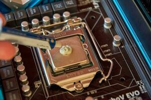 applying thermal paste to the central processor of the motherboard close up photo