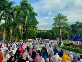 sholat idul fitri. indonesian muslim community are doing eid al fitr prayer in outdoor area. sholat idul adha in college field with words means independent college photo