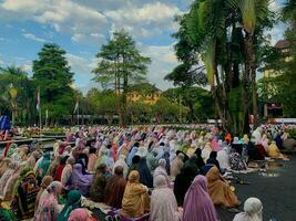 sholat idul fitri. indonesian muslim community are doing eid al fitr prayer in outdoor area. sholat idul adha in college field with words means independent college photo