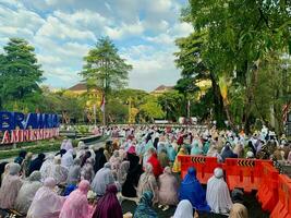 sholat idul fitri. indonesian muslim community are doing eid al fitr prayer in outdoor area. sholat idul adha in college field with words means independent college photo