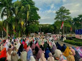 sholat idul fitri. indonesian muslim community are doing eid al fitr prayer in outdoor area. sholat idul adha in college field with words means independent college photo