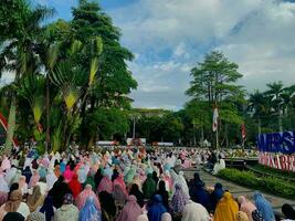 sholat idul fitri. indonesian muslim community are doing eid al fitr prayer in outdoor area. sholat idul adha in college field with words means independent college photo