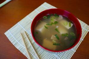 miso soup or Japanese miso soup in bowl on the table. Japanese cuisine in the form of soup with dashi ingredients, tofu, seafood, vegetables, and topped with miso to taste photo