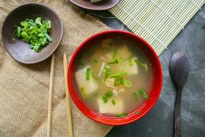 miso sopa o japonés miso sopa en cuenco en el mesa. japonés cocina en el formar de sopa con dashi ingredientes, tofu, mariscos, verduras, y coronado con miso a gusto foto