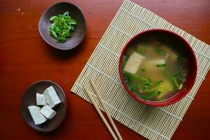 miso sopa o japonés miso sopa en cuenco en el mesa. japonés cocina en el formar de sopa con dashi ingredientes, tofu, mariscos, verduras, y coronado con miso a gusto foto