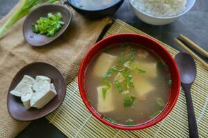 miso sopa o japonés miso sopa en cuenco en el mesa. japonés cocina en el formar de sopa con dashi ingredientes, tofu, mariscos, verduras, y coronado con miso a gusto foto