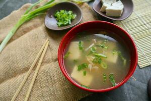 miso soup or Japanese miso soup in bowl on the table. Japanese cuisine in the form of soup with dashi ingredients, tofu, seafood, vegetables, and topped with miso to taste photo