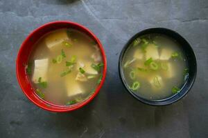 miso sopa o japonés miso sopa en cuenco en el mesa. japonés cocina en el formar de sopa con dashi ingredientes, tofu, mariscos, verduras, y coronado con miso a gusto foto