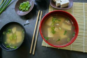 miso soup or Japanese miso soup in bowl on the table. Japanese cuisine in the form of soup with dashi ingredients, tofu, seafood, vegetables, and topped with miso to taste photo