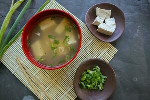miso soup or Japanese miso soup in bowl on the table. Japanese cuisine in the form of soup with dashi ingredients, tofu, seafood, vegetables, and topped with miso to taste photo