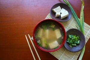 miso soup or Japanese miso soup in bowl on the table. Japanese cuisine in the form of soup with dashi ingredients, tofu, seafood, vegetables, and topped with miso to taste photo