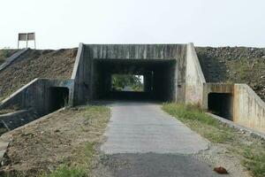 small tunnel. Outdoor scenery of empty street pass through a small tunnel under the highway and agricultural fields Space for text. photo