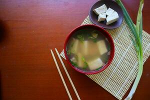 miso sopa o japonés miso sopa en cuenco en el mesa. japonés cocina en el formar de sopa con dashi ingredientes, tofu, mariscos, verduras, y coronado con miso a gusto foto