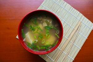 miso sopa o japonés miso sopa en cuenco en el mesa. japonés cocina en el formar de sopa con dashi ingredientes, tofu, mariscos, verduras, y coronado con miso a gusto foto