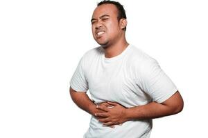 Photo of young unwell sick ill man with tshirt hold hand on stomach suffers pain isolated on white background