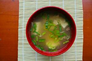 miso sopa o japonés miso sopa en cuenco en el mesa. japonés cocina en el formar de sopa con dashi ingredientes, tofu, mariscos, verduras, y coronado con miso a gusto foto