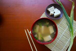 miso sopa o japonés miso sopa en cuenco en el mesa. japonés cocina en el formar de sopa con dashi ingredientes, tofu, mariscos, verduras, y coronado con miso a gusto foto