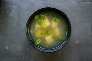 miso soup or Japanese miso soup in bowl on the table. Japanese cuisine in the form of soup with dashi ingredients, tofu, seafood, vegetables, and topped with miso to taste photo