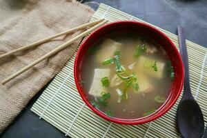 miso soup or Japanese miso soup in bowl on the table. Japanese cuisine in the form of soup with dashi ingredients, tofu, seafood, vegetables, and topped with miso to taste photo