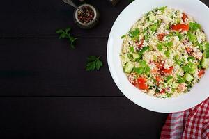 Traditional Lebanese Salad Tabbouleh. Couscous with parsley, tomato, cucumber, lemon and olive oil. Middle Eastern cuisine. Top view, copy space photo