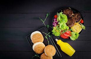 Burger cooking. Big sandwich - hamburger burger with beef,  tomato, cheese, pickled cucumber and red onion. Top view photo