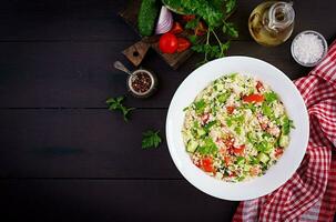 Traditional Lebanese Salad Tabbouleh. Couscous with parsley, tomato, cucumber, lemon and olive oil. Middle Eastern cuisine. Top view, copy space photo