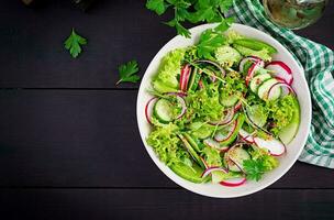 Healthy vegan food. Vegetarian vegetable salad of radish, cucumbers, lettuce  and red onion.  Top view, copy space photo