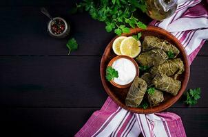 Dolma. Stuffed grape leaves with rice and meat on dark table. Middle eastern cuisine. Top view, overhead, copy space photo