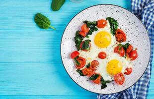 Breakfast. Ketogenic diet food. Fried egg, spinach, and tomatoes. Keto, paleo breakfast. Top view, copy space photo