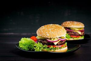 Big sandwich - hamburger burger with beef,  tomato, cheese, pickled cucumber and red onion. photo