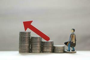 Business man standing on stack of coins money and red arrow graph on natural green background, investment and business concept photo