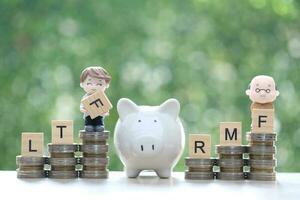 Businessman and Seniorman on stack of coins money on natural green background photo