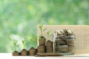 Finance, Gold coin money in the glass bottle with banking account book on natural green background, Save money for prepare in future and pension retirement concept photo